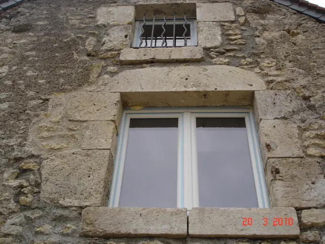 Fenêtre et soupirail à encadrement en pierre de taille sur une façade ancienne restaurée
