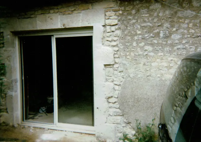 Baie vitrée créée dans un mur en pierre avec encadrement en pierre de taille