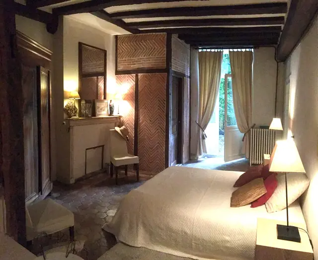 Chambre rénovée avec poutres apparentes et cheminée