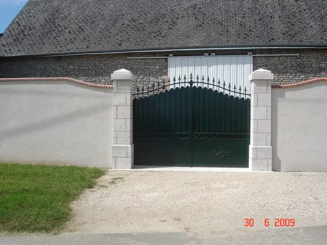 Mur de clôture enduit avec piliers en pierre de taille et portail en fer forgé