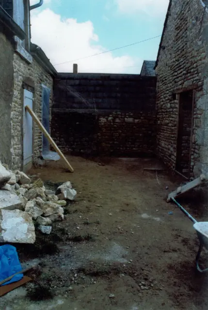 Construction d'un mur en pierre : chantier en cours dans une cour de ferme