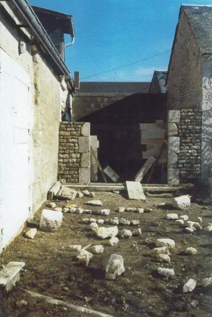 Mur en pierre en cours de montage, pierres de récupération au sol