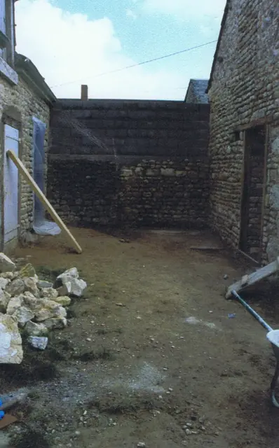 Cour en travaux : reprise d'un mur en pierre entre deux bâtiments