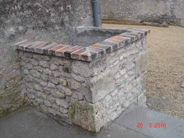 Puits en pierre restauré avec margelle en brique