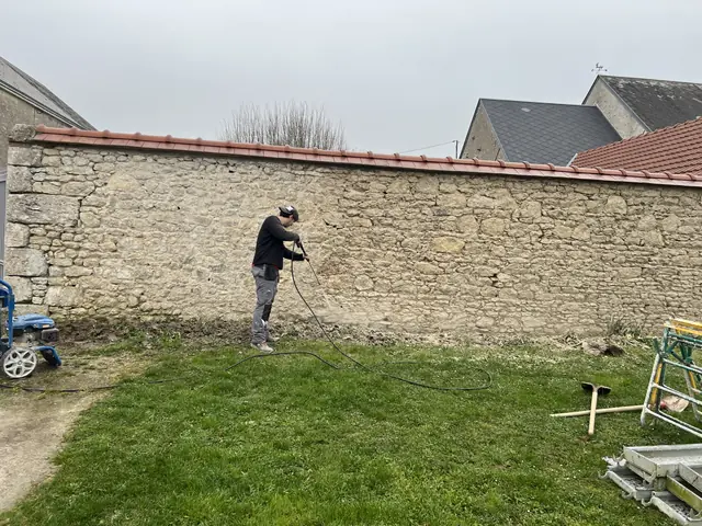 Maçon Aktibat au travail sur la restauration d'un mur de clôture en pierre