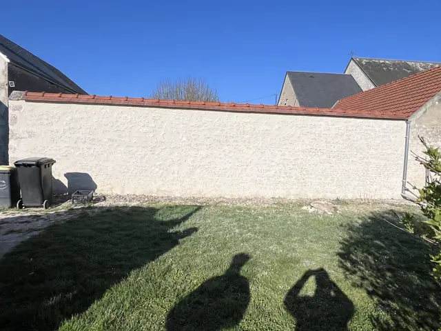 Mur de clôture en pierre enduit à la chaux après restauration